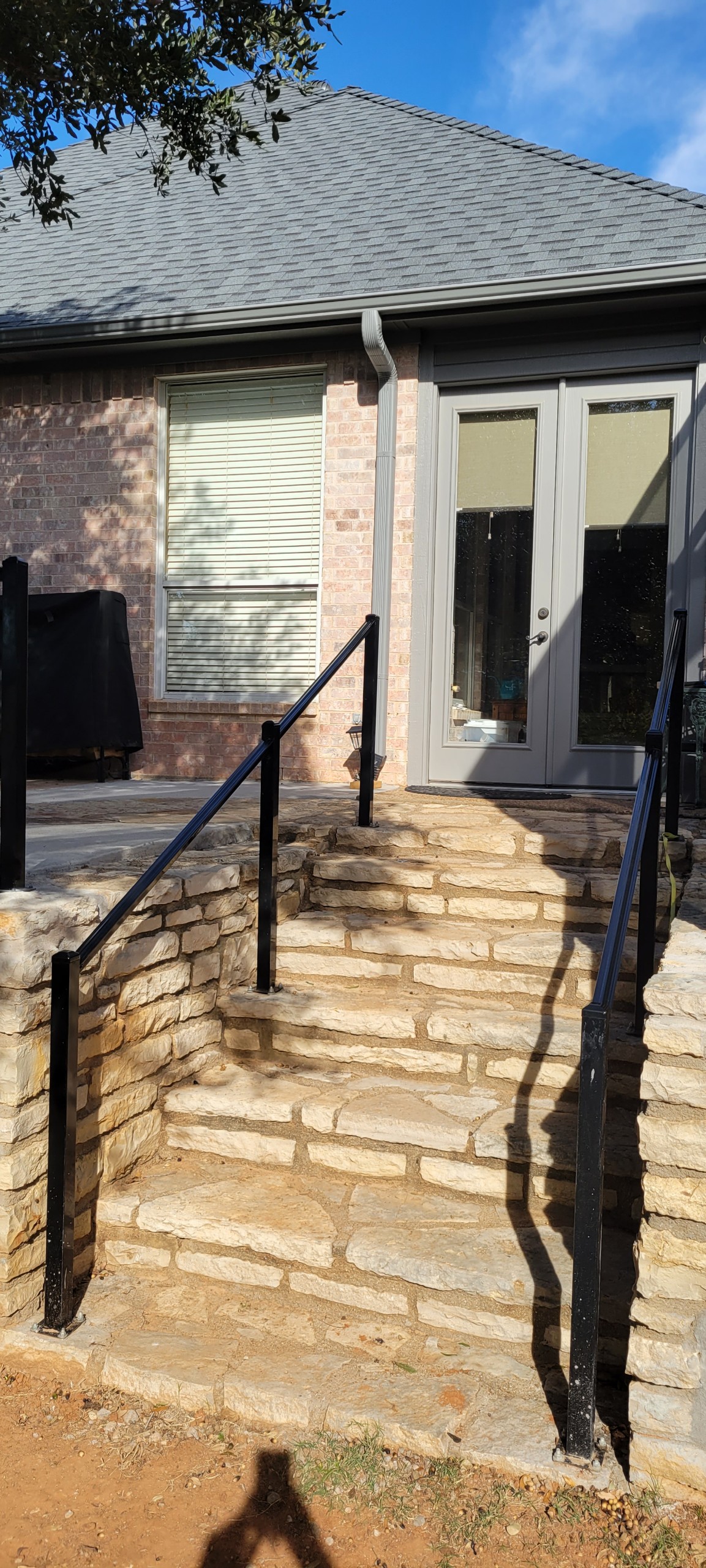 Black ornamental metal railing along stone entry steps on a Granbury-area home