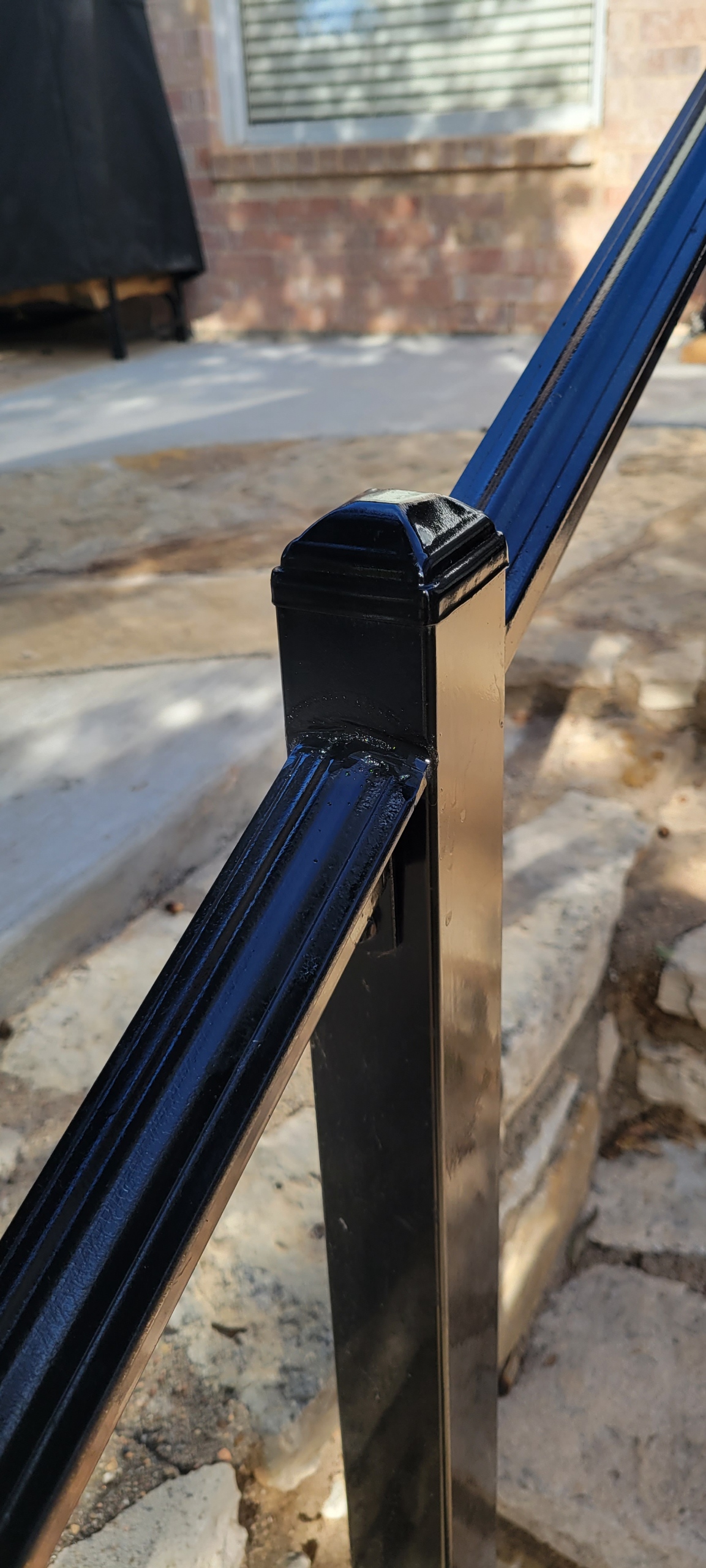 Close-up of a welded and finished black ornamental metal fence post cap