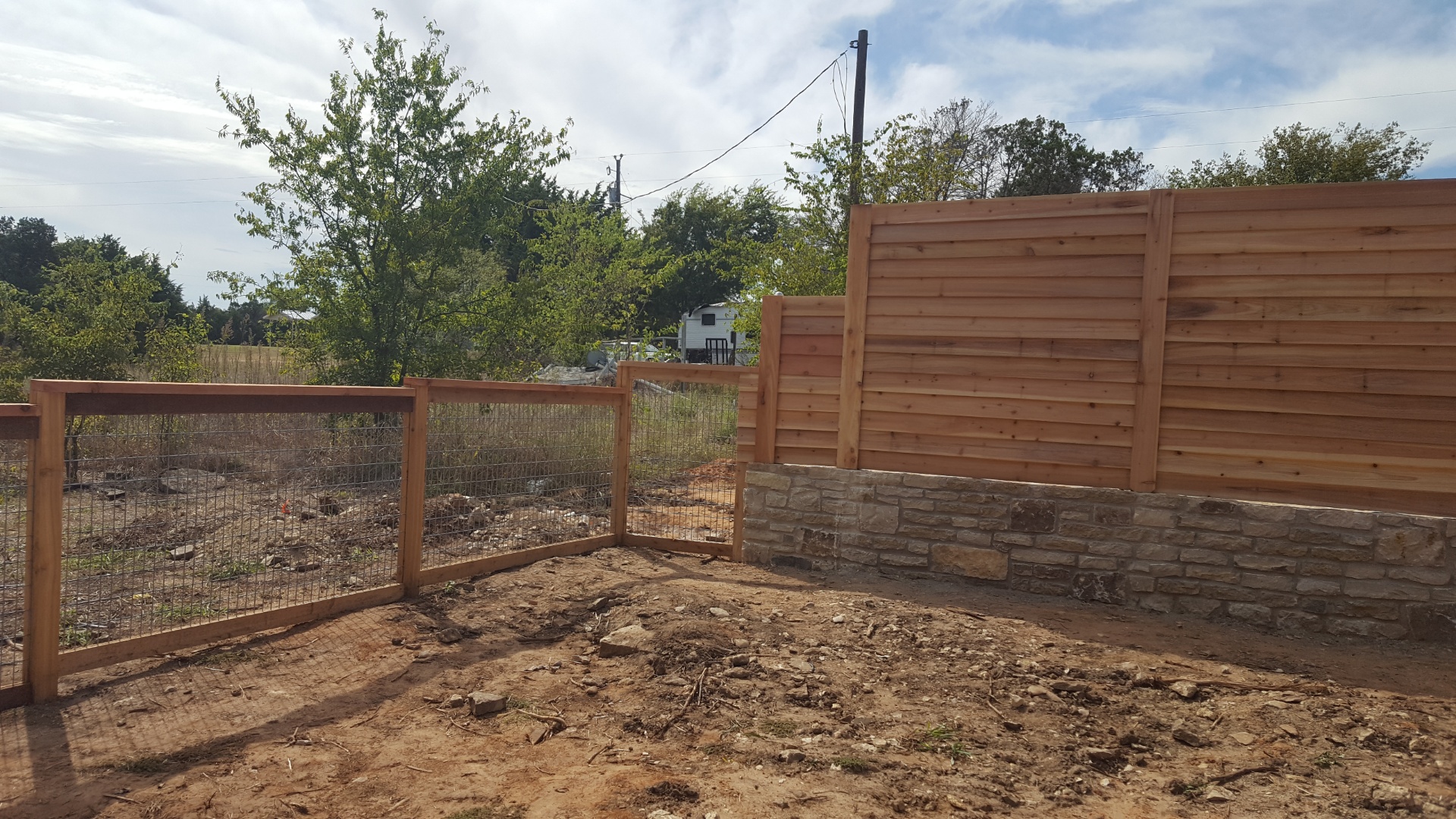 Cedar wood fence panel repaired and rebuilt to meet a stone wall foundation