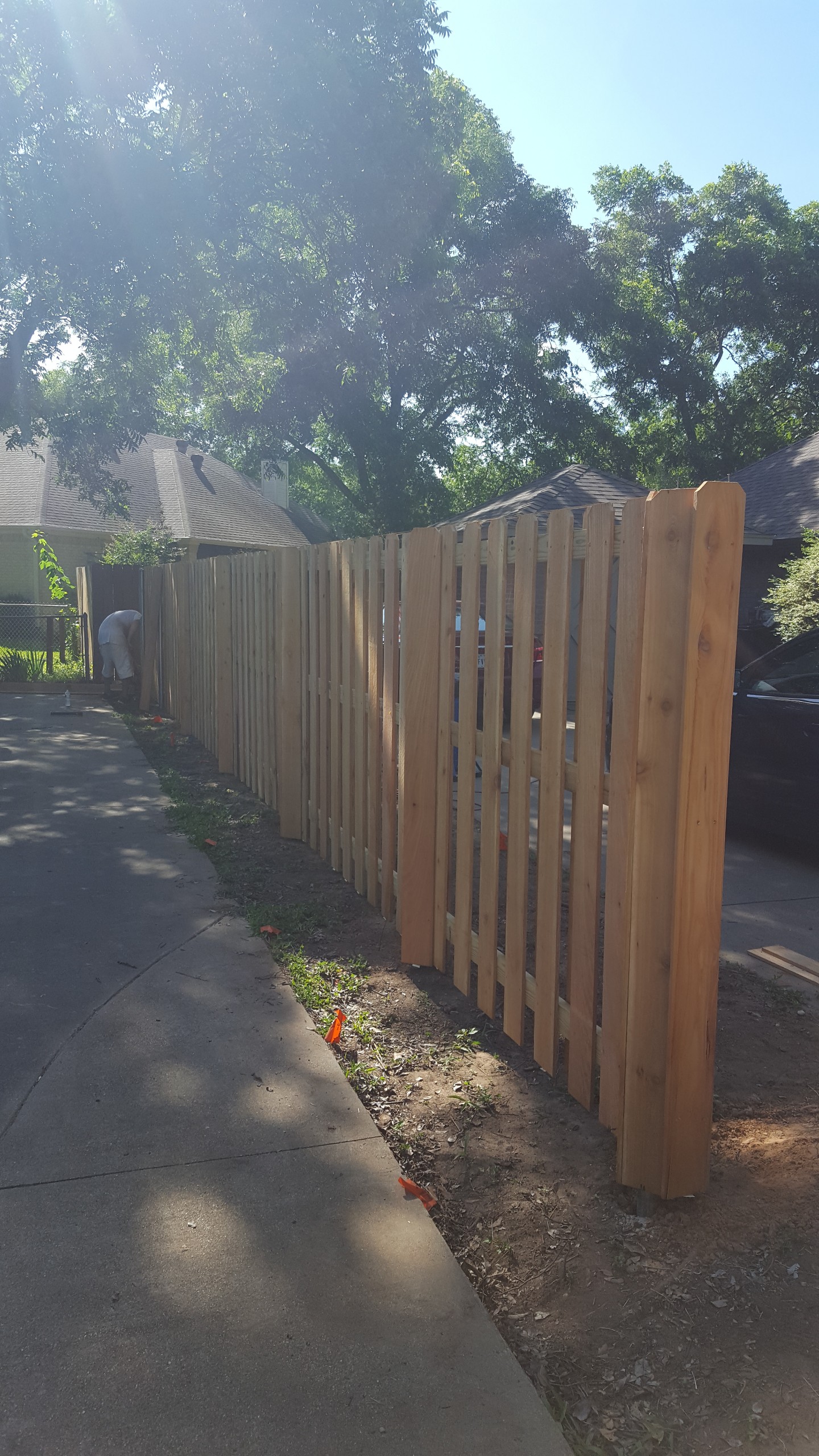 All Around Fencing crew member installing a cedar picket fence along a driveway