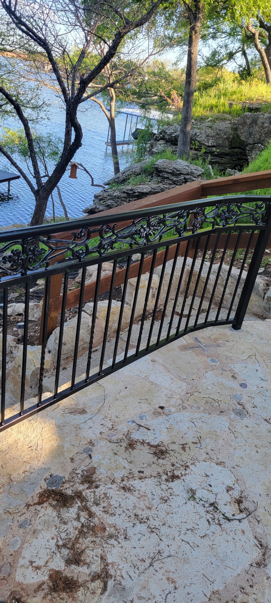 Black scrolled ornamental iron railing following stone steps down to a Lake Granbury property